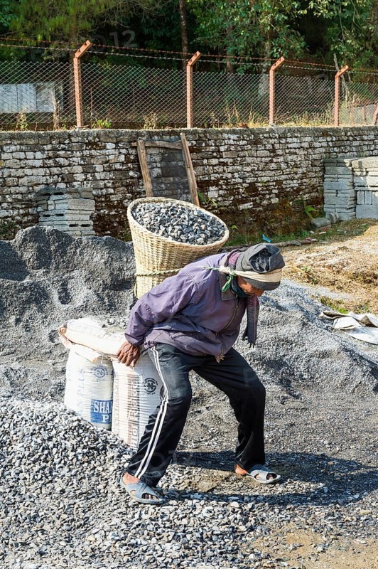 Nepalese man carrying stones for construction on his back