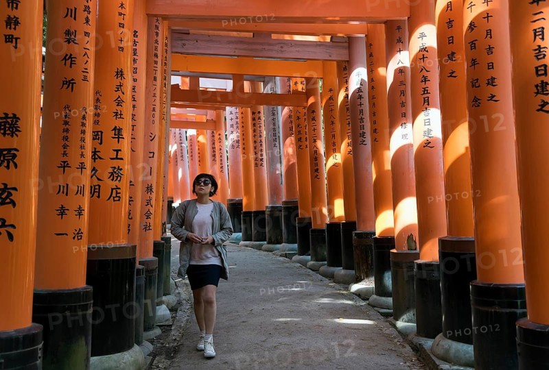 Young woman on a pathway lined with torii gates