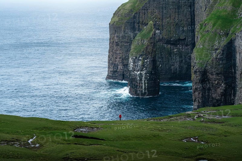 A person standing in the distance in front of Asmundarstakkur cliff