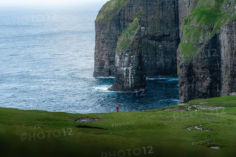A person standing in the distance in front of Asmundarstakkur cliff