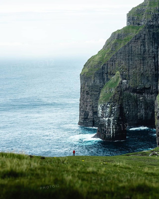 A person standing in the distance in front of Asmundarstakkur cliff