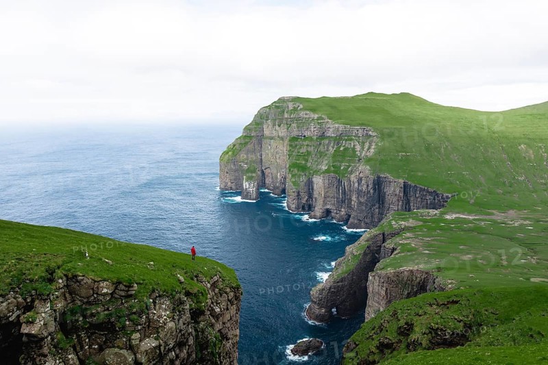 A person standing in the distance in front of Asmundarstakkur cliff