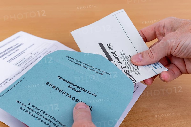 Man puts his folded ballot paper into the ballot paper envelope for the election of members of the German Bundestag on 26.09.2021