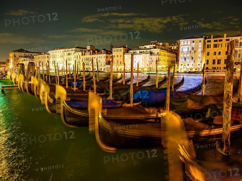Gondolas in front of historic house facades in the Grand Canal at night