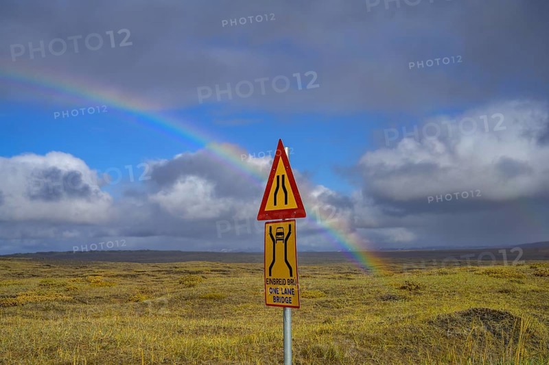 Rainbow over the autumn coloured landscape and road sign one lane bridge