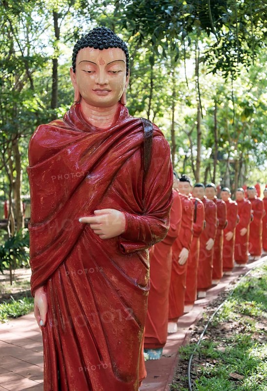 Statues of monks walking behind Buddha