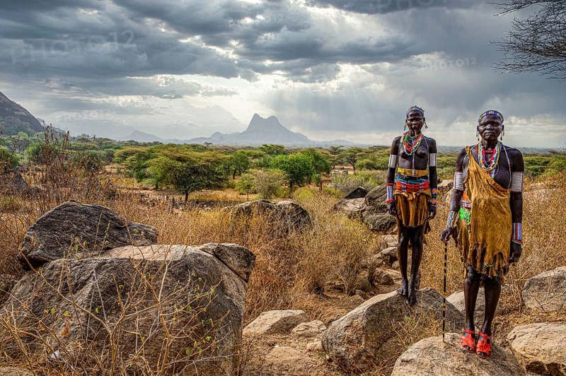 Traditional dressed young girls from the Laarim tribe standing on a rock