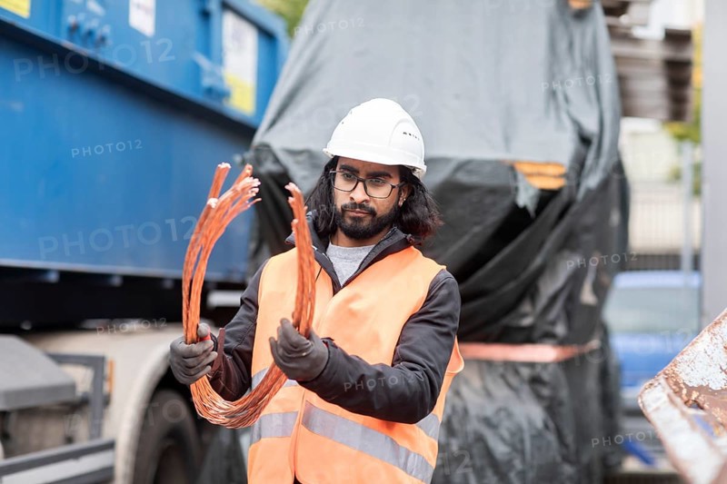 Technician with beard and helmet working in a recycling yard