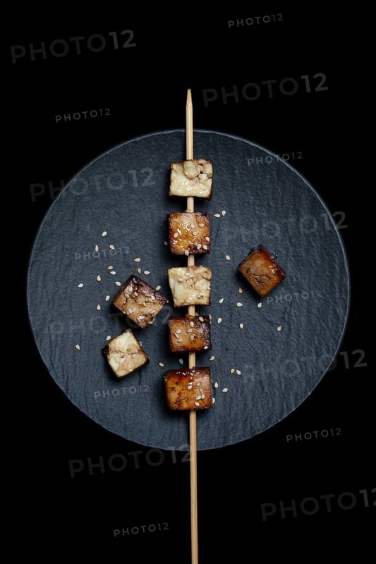 Fried tofu cubes with wooden skewer on plate