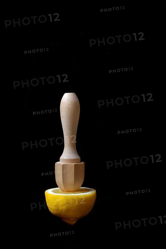 Lemon and lemon squeezer against a black background