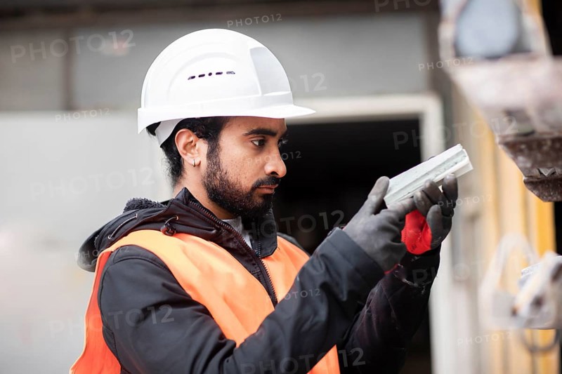Technician with beard and helmet works in a workshop