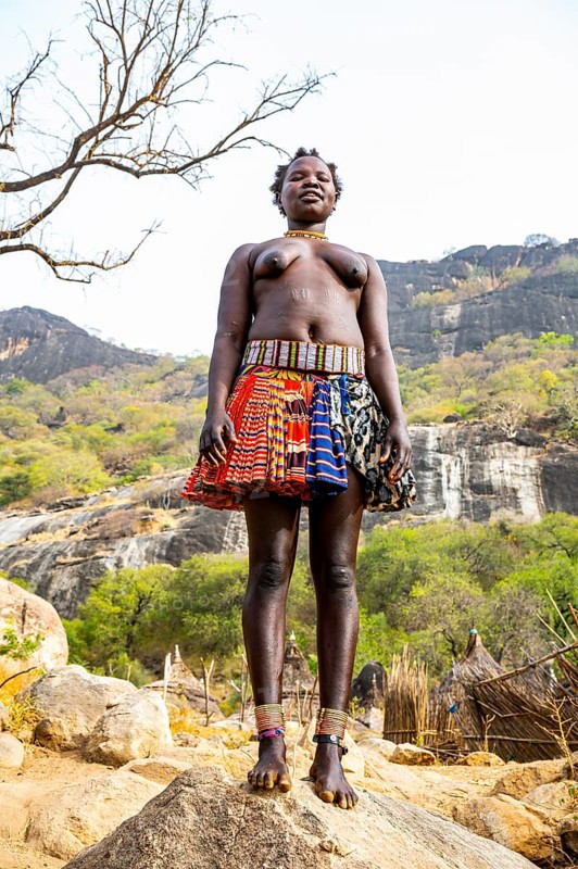 Traditional dressed young girls from the Laarim tribe standing on a rock