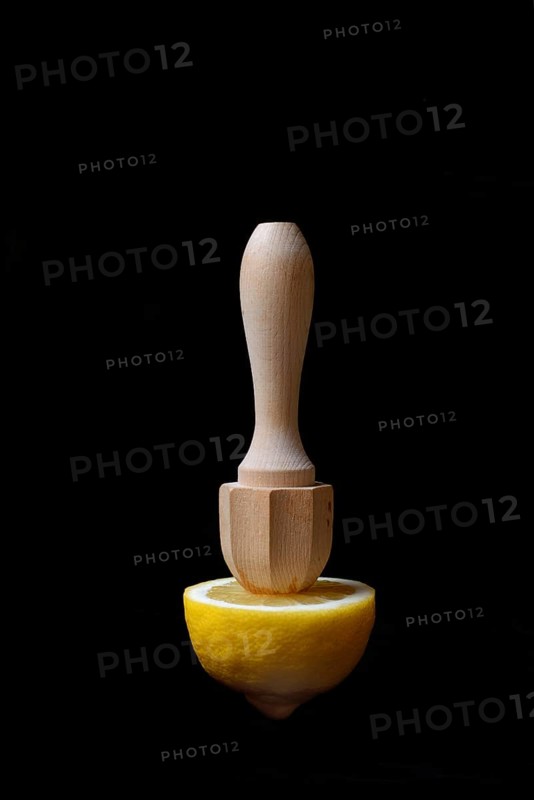 Lemon and lemon squeezer against a black background