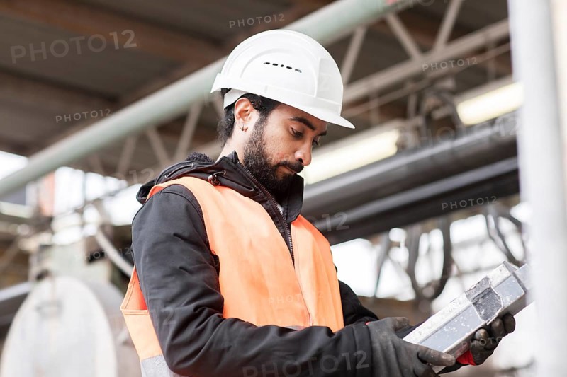 Technician with beard and helmet works in a workshop