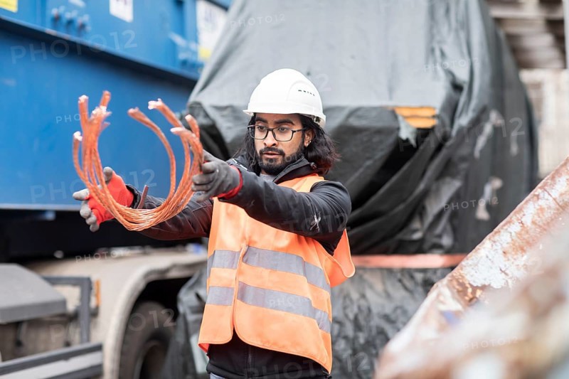 Technician with beard and helmet working in a recycling yard