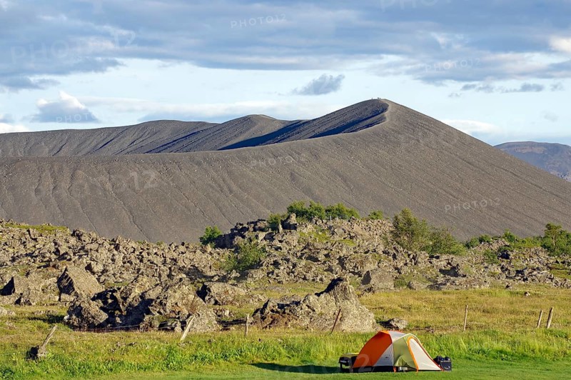 Tent in front of volcanic cone and lava