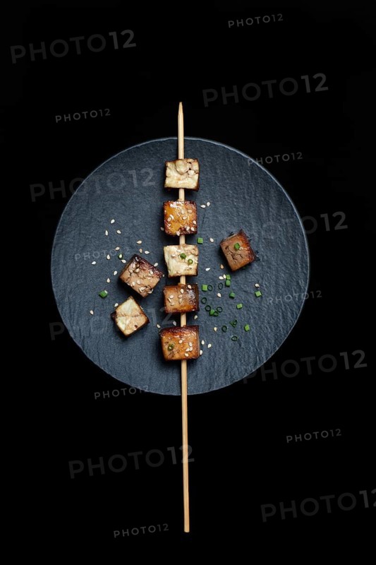 Fried tofu cubes with wooden skewer on plate
