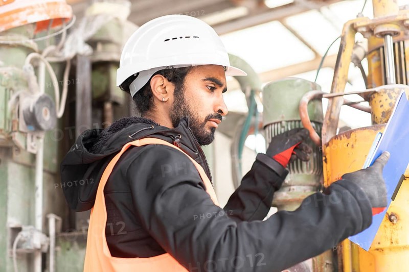 Technician with beard and helmet works in a workshop