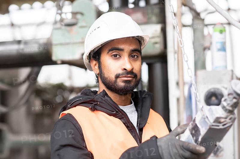 Technician with beard and helmet works in a workshop
