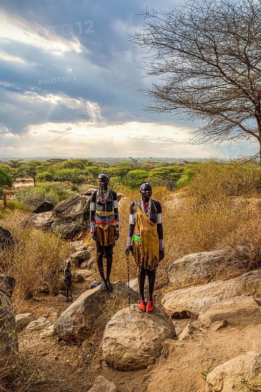 Traditional dressed young girls from the Laarim tribe standing on a rock
