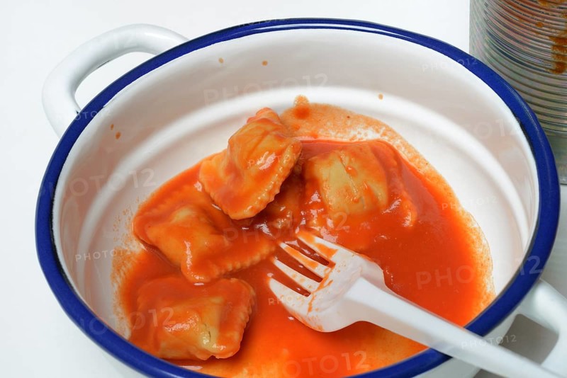 Ravioli with tomato sauce in bowl with plastic fork