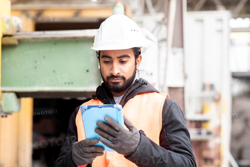 Technician with beard and helmet works in a workshop