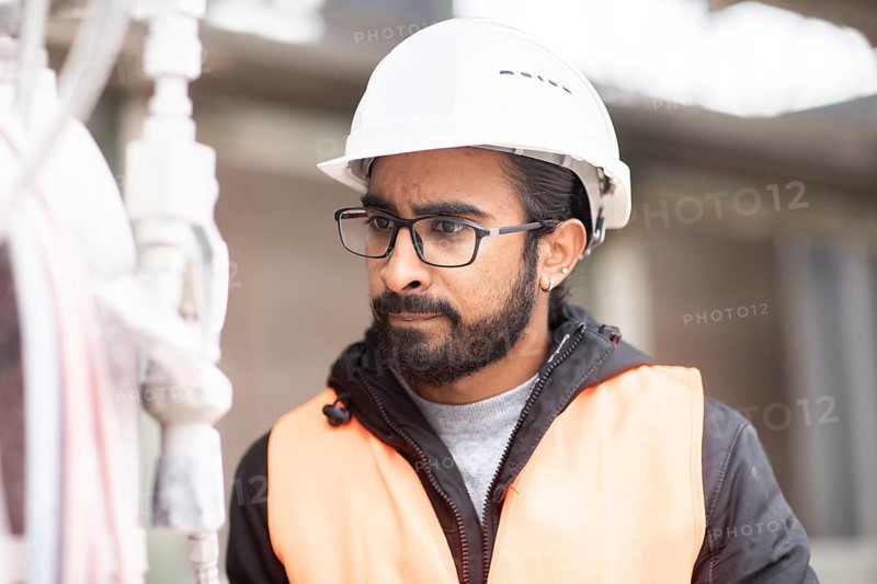 Technician with beard and helmet works in a workshop
