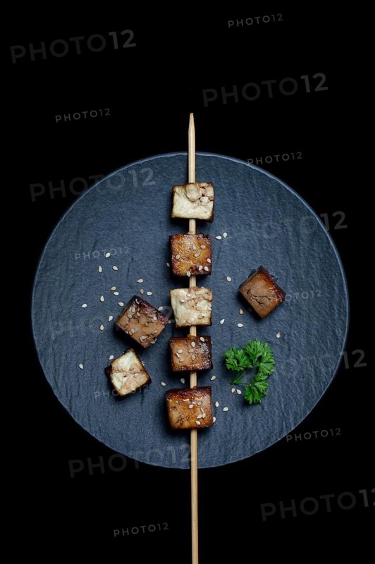 Fried tofu cubes with wooden skewer on plate