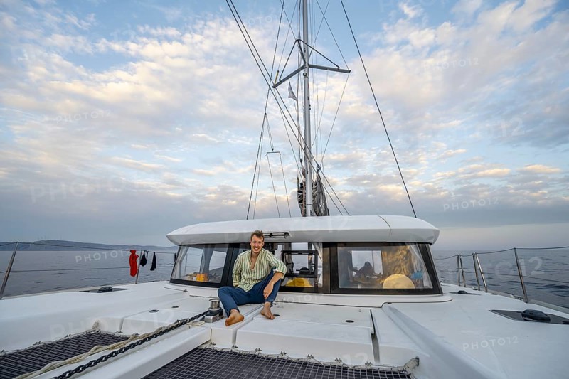 Young man sitting on the deck of a sailing catamaran