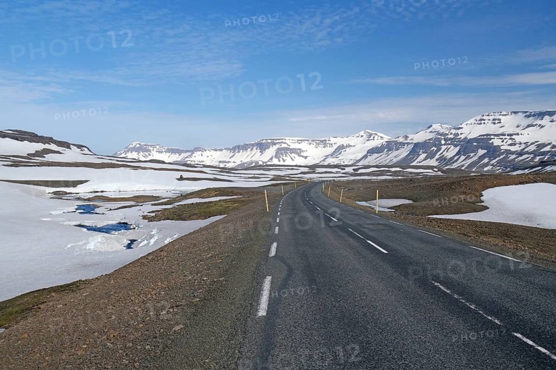 Road leads through barren mountain landscape with snow and ice