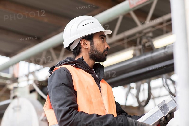 Technician with beard and helmet works in a workshop