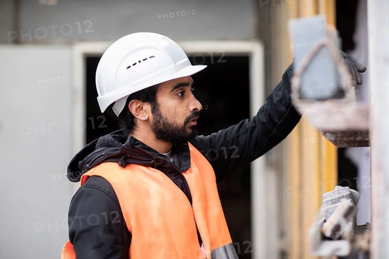 Technician with beard and helmet works in a workshop