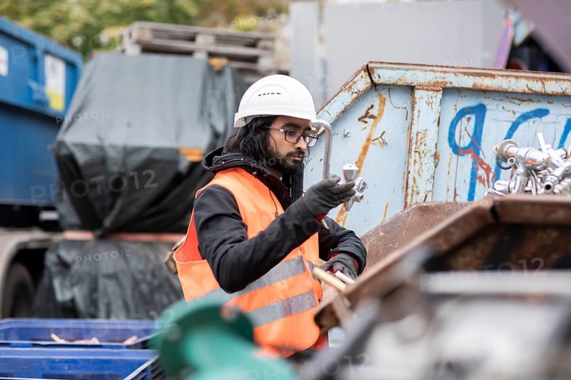 Technician with beard and helmet working in a recycling yard