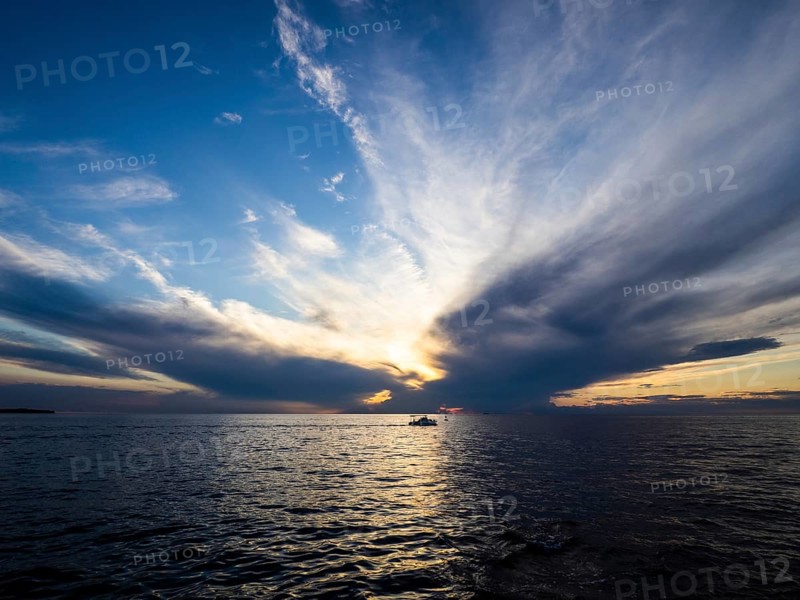 Dark clouds over the sea in front of sunset