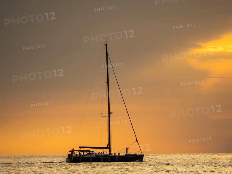 Sailing ship with gathered sails in front of dark clouds