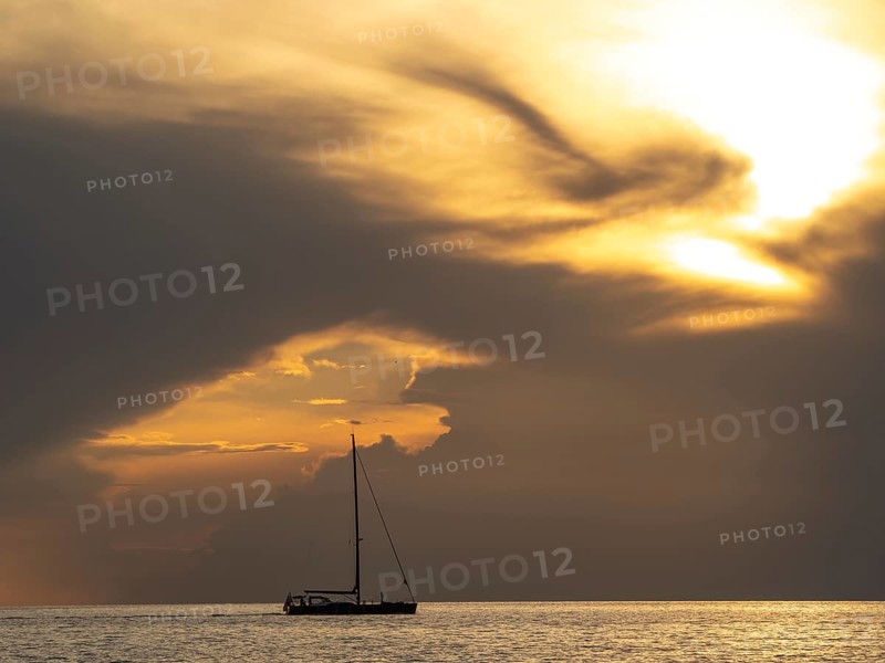Sailing ship with gathered sails in front of dark clouds