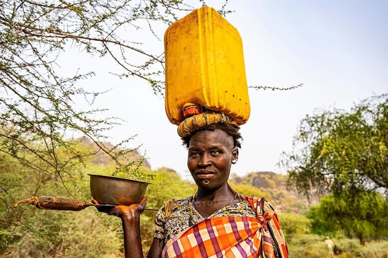 Woman with a water caniister on her head
