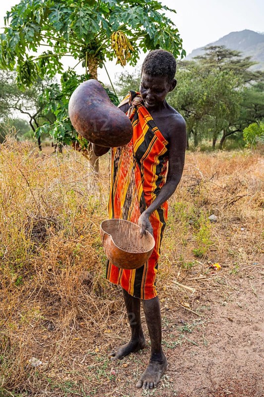 Laarim woman filtering Sorghum in a carabass