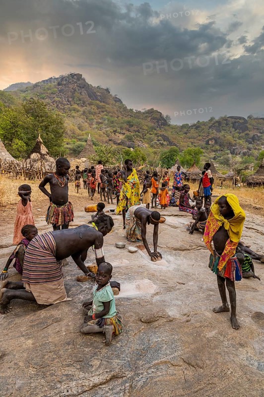 Young girls grinding Sorghum on a rock
