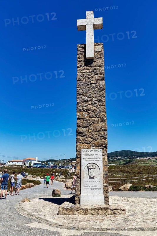 Tourists at the monument with stone cross and information board