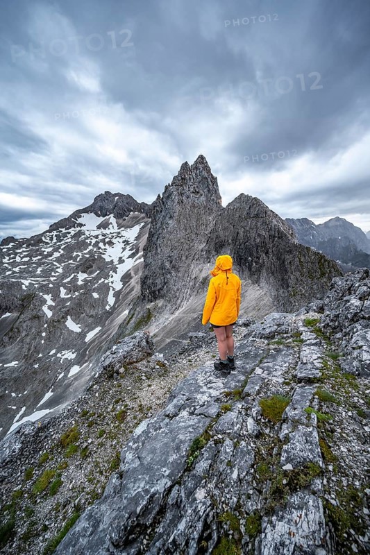 Hiker looking at mountains under dramatic clouds