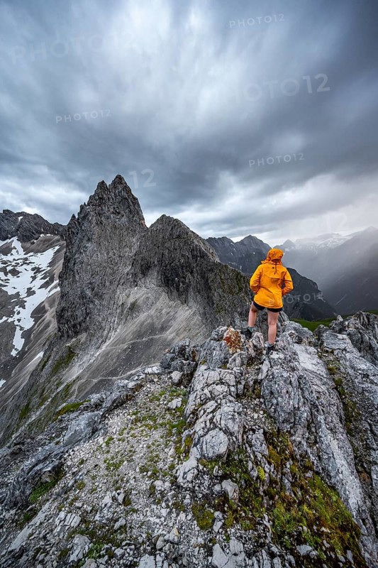 Hiker looking at mountains under dramatic clouds
