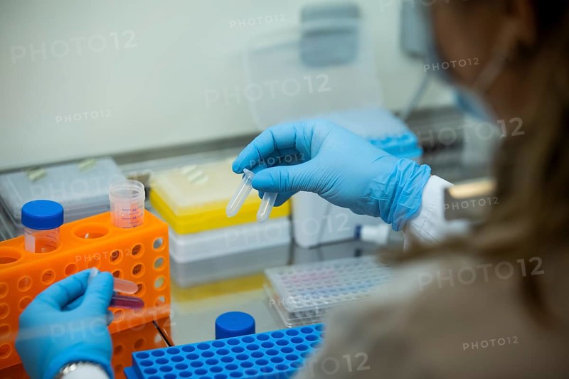 Medical laboratory assistant holding reaction vessels with samples