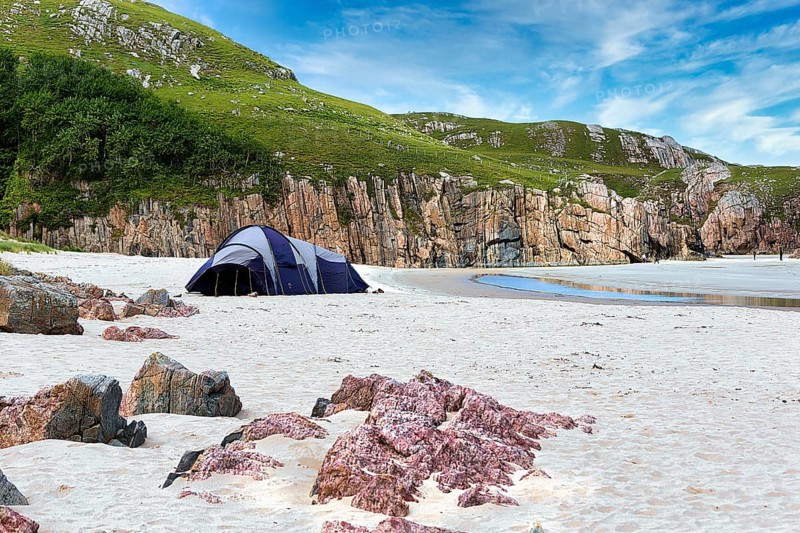 Tent in a bay with rocks and sandy beach