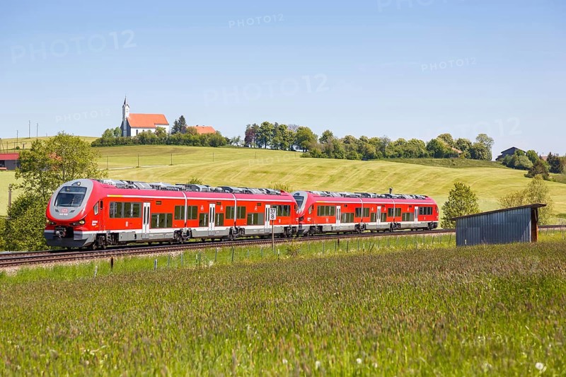 Pesa Link Regional train of Deutsche Bahn DB with church St. Alban in Allgaeu Bavaria in Aitrang