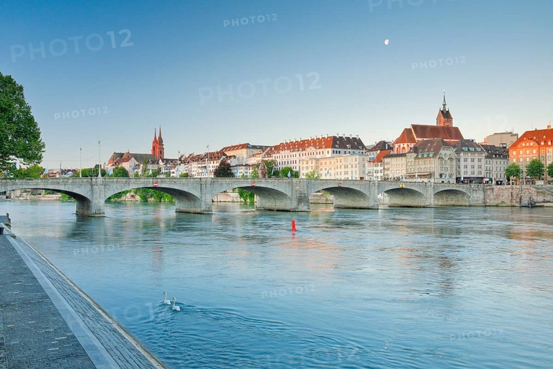 View from the banks of the Rhine along the river promenade to the old town of Basel with the Basel Cathedral