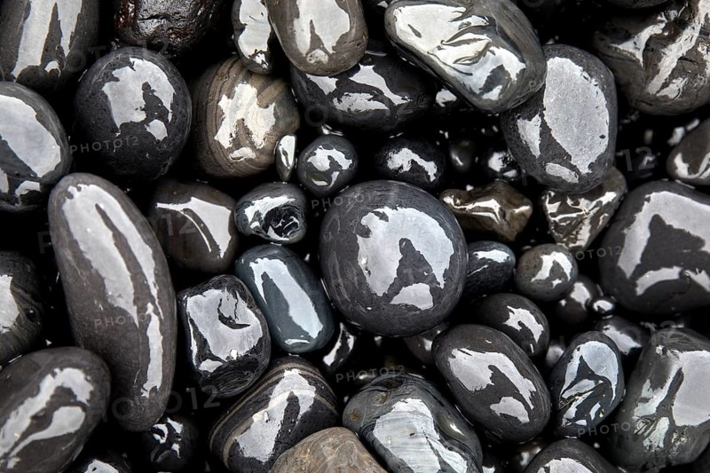 Wet rounded stones with reflection on the beach