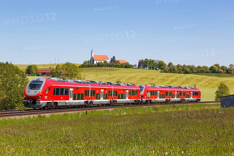 Pesa Link Regional train of Deutsche Bahn DB with church St. Alban in Allgaeu Bavaria in Aitrang
