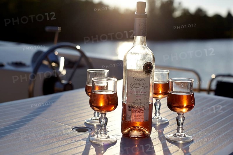 Liqueur with glasses in the backlight on houseboat at the Lot