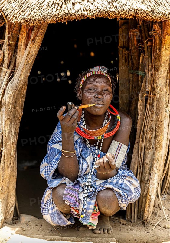 Woman with beauty scars from the Toposa tribe smoking a pipe